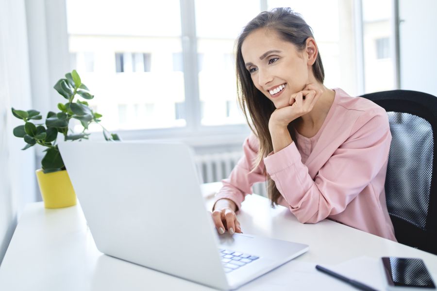 Happy young businesswoman working with laptop in office